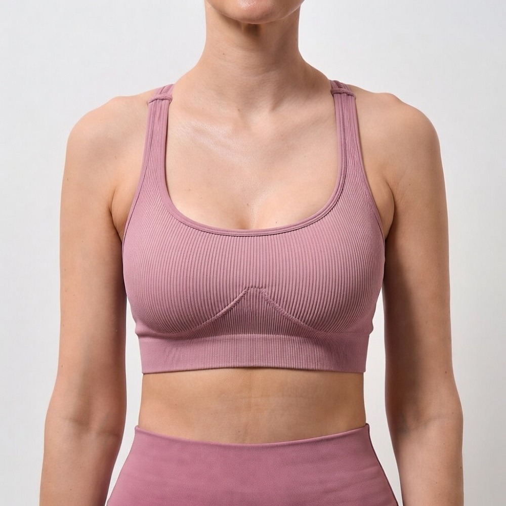 A headless, square clinical after photograph (1:1 ratio) of the identical white woman from image 104 png, now exhibiting flawlessly symmetrical, naturally contoured, and beautifully proportioned breast appearance  Both breasts are evenly uplifted and voluminous following a complex corrective combined Breast Augmentation & Lift procedure managed by Dina Elite for GCC patients, wearing the same pink athletic outfit against the sterile white background 