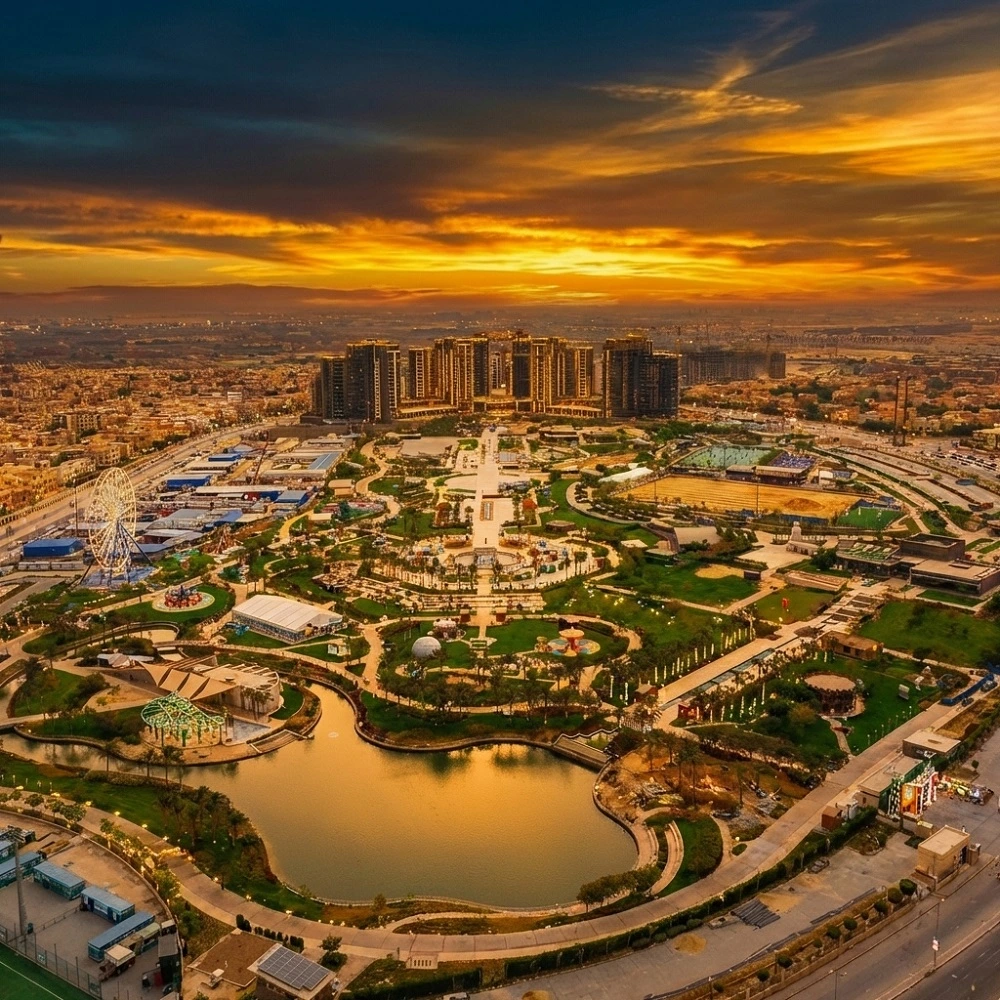 Panoramic sunset view of Zed Park in Sheikh Zayed, Giza, a premier destination for leisure and wellness integrated into Dina Elite luxury medical tourism programs for clients from Saudi Arabia, United Arab Emirates, Qatar, Kuwait, Bahrain, Oman, Jordan, Iraq, Lebanon, Libya, Palestine, Yemen, Syria, Sudan, Morocco, Algeria, Tunisia, Mauritania, Djibouti, Somalia, and Comoros 